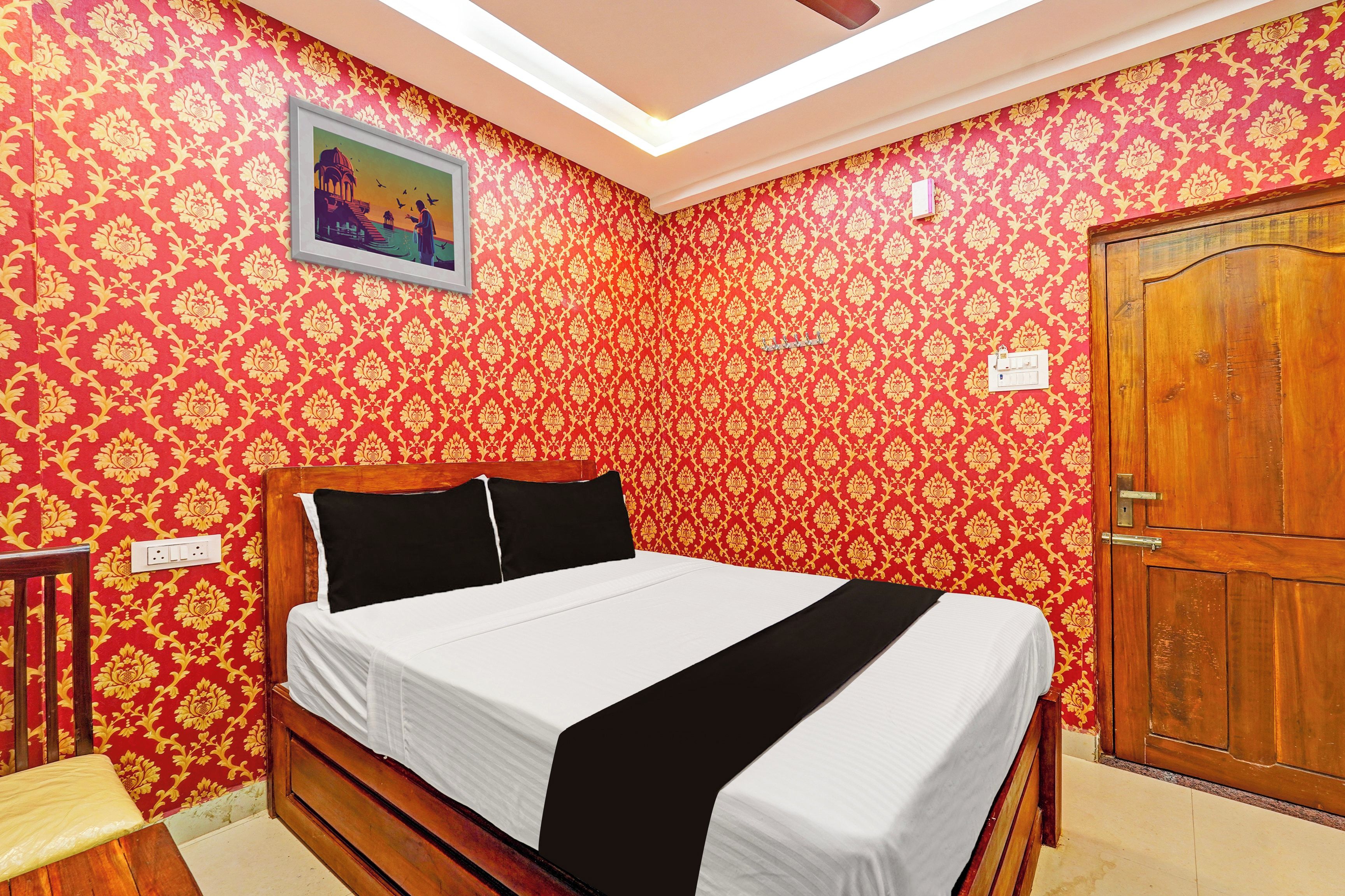A room with a bed, a wooden door, and patterned wallpaper.