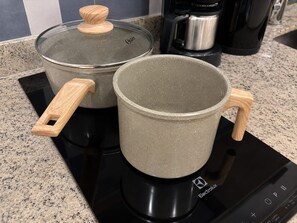 Two ceramic pots with wooden handles on a black induction cooktop. - SETIN 2105 (São Paulo)