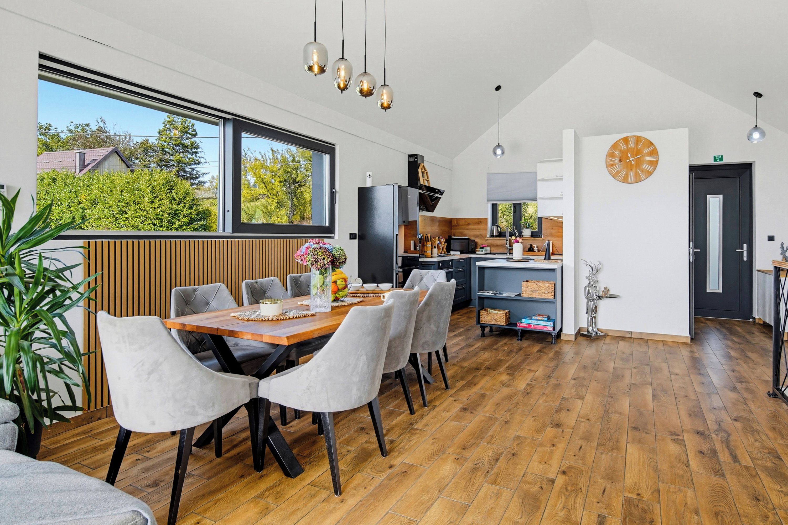 Una cocina moderna con comedor, piso de madera y un ventanal grande.