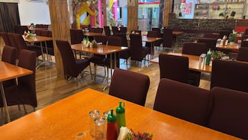 A restaurant with multiple tables and chairs, a bar area, and a decorative wall.