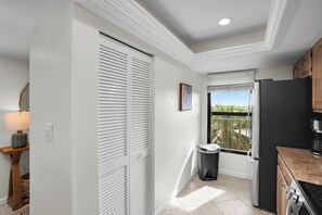 A modern kitchen with white cabinetry, a black refrigerator, and a window with a view of greenery. - Grandview 2BR | Walk to Beach & Marco Walk (Marco Island)