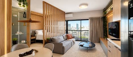 A modern living room with a sofa, coffee table, and a dining area with chairs and a table.