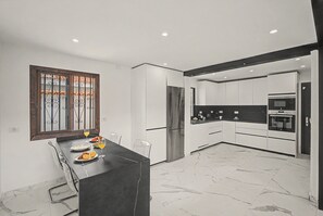 Una cuina moderna amb armaris blancs, un frigorífic d'acer inoxidable i un taulell negre.