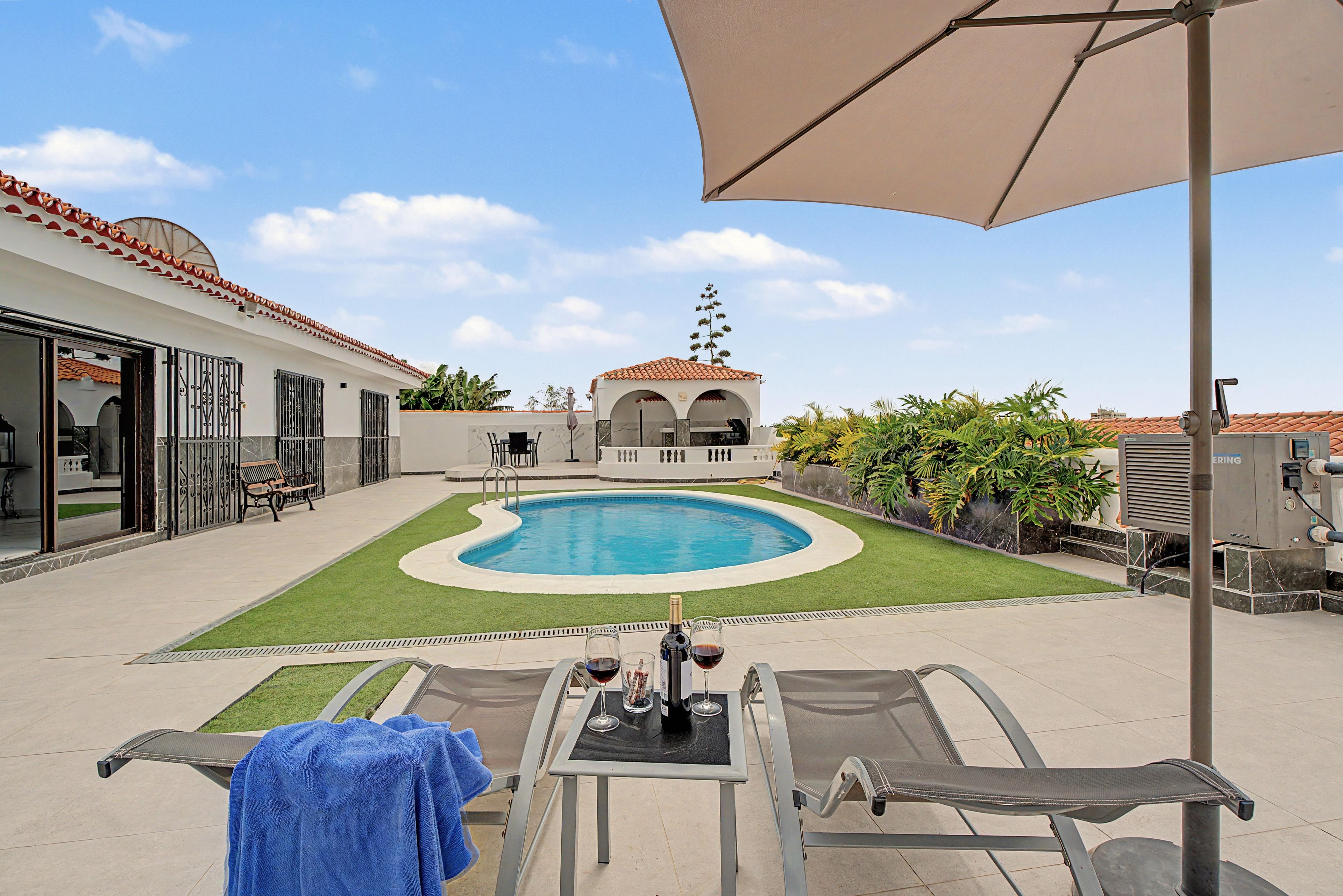 Zona junto a la piscina con piscina, sillas de descanso y una mesa con bebidas.