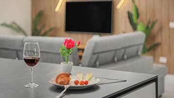 Una mesa de comedor con una copa de vino, un plato con un croissant, queso y tomates, y un florero.