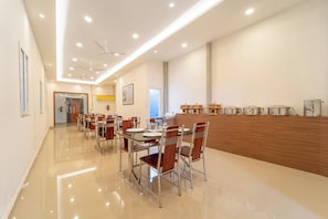 Un espace repas moderne doté d’un long comptoir, de plusieurs tables et de chaises.
