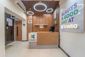 Un comptoir d’accueil orné du logo « treebo », doté d’un écran numérique et d’une affiche motivante sur laquelle on peut lire : « CHAQUE JOUR EST UN BON JOUR CHEZ treebo ».