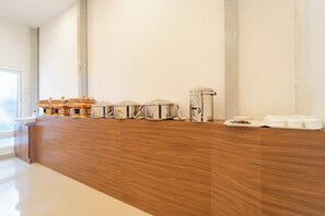 Een lange houten toonbank met verschillende artikelen voor de horeca, zoals bakken en bestek.