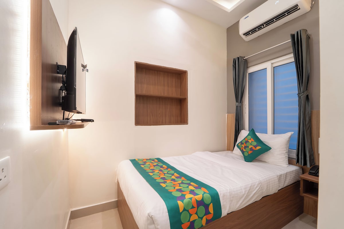 Une chambre d’hôtel équipée d’un lit, d’un téléviseur fixé au mur, d’un appareil de climatisation et d’une fenêtre avec des rideaux.