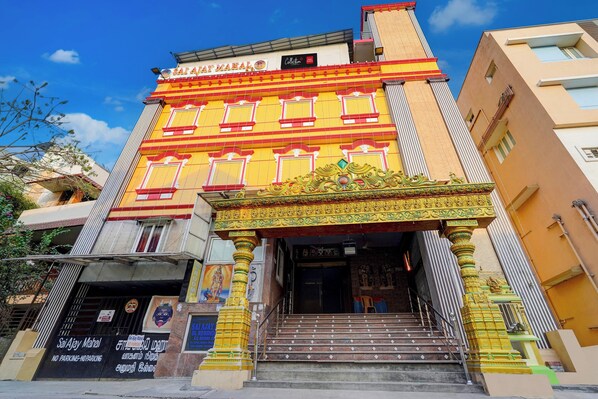 A building with a prominent entrance, a staircase leading up to it, and a sign above the entrance.