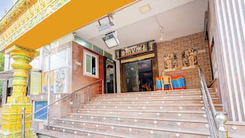 Una escalera conduce a una sala de oficina con un letrero de advertencia, una pared de piedra con estatuas y un pilar amarillo con detalles intrincados.