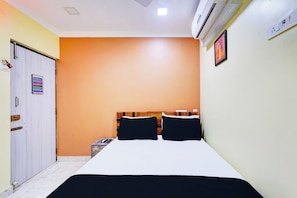 A bedroom with a bed, a wardrobe, an air conditioning unit, and a wall-mounted picture.