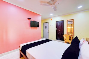 Una habitación de hotel con una cama, un ventilador de techo, un televisor y una puerta.