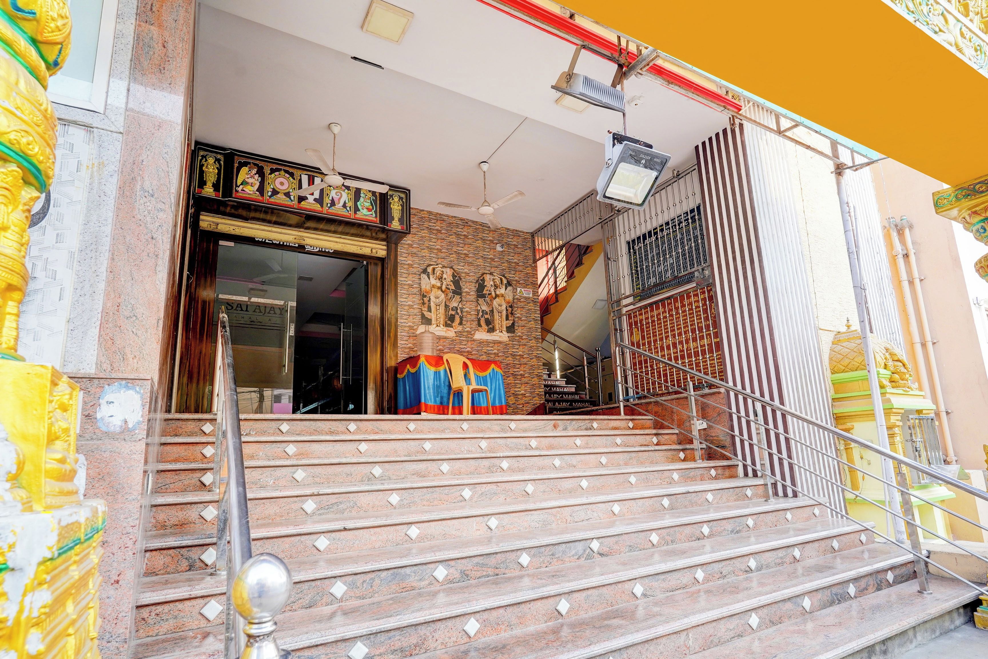 A temple entrance with steps leading up to a door, a statue, and a signboard.