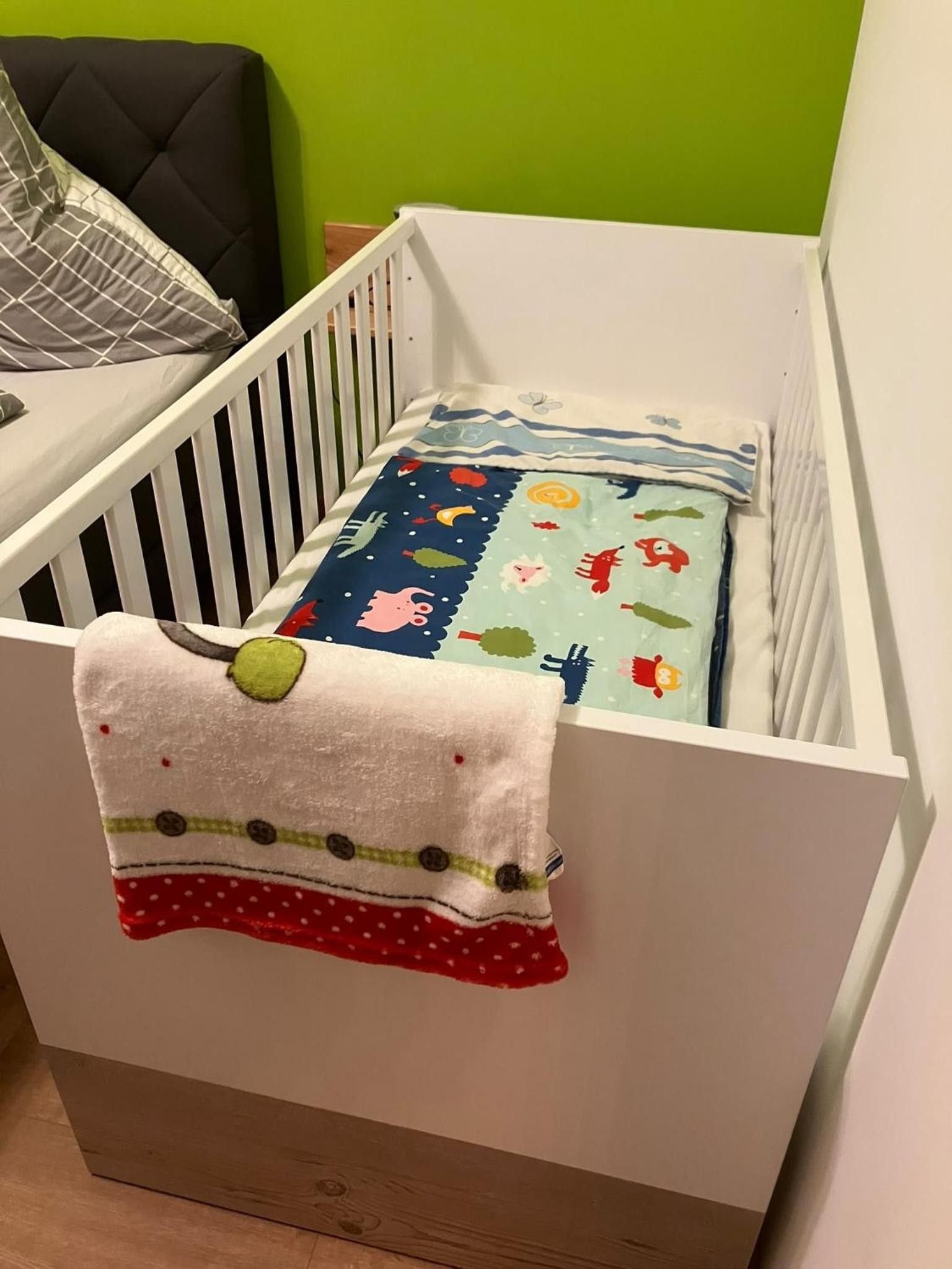 A white crib with a colorful blanket and a pillow.