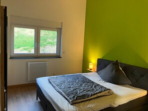 Ein Schlafzimmer mit einem Bett, einem Fenster, einer Heizung und einer grünen Wand.