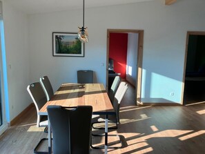 Ein Essbereich mit Holztisch und -stühlen, einer Hängeleuchte und einem gerahmten Bild an der Wand.