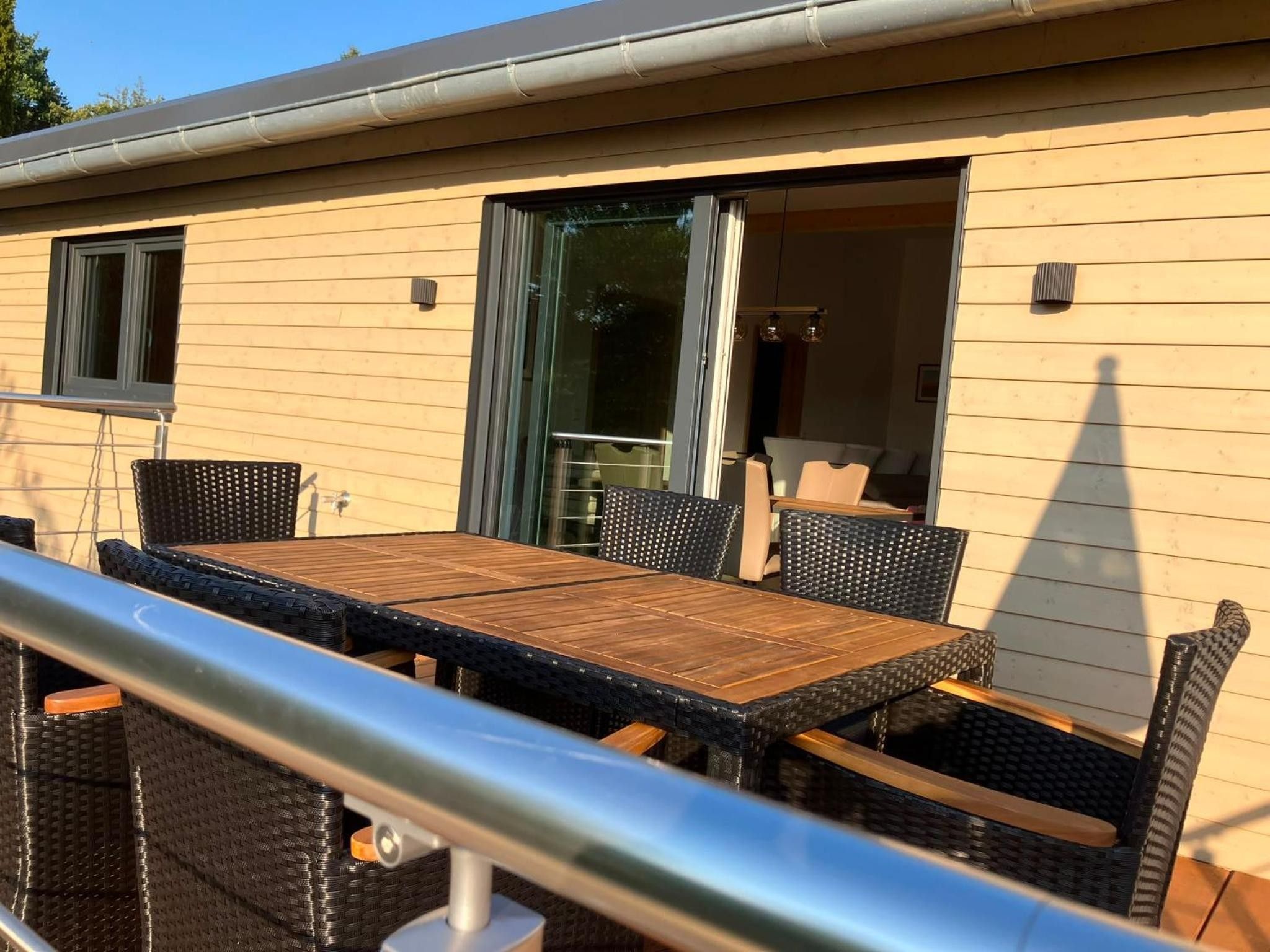 An outdoor patio with a table and chairs, a sliding glass door, and a railing.