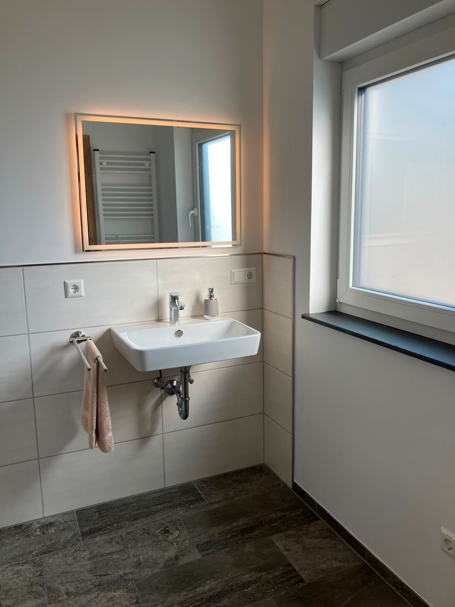A bathroom with a white sink, a mirror, and a towel rack.
