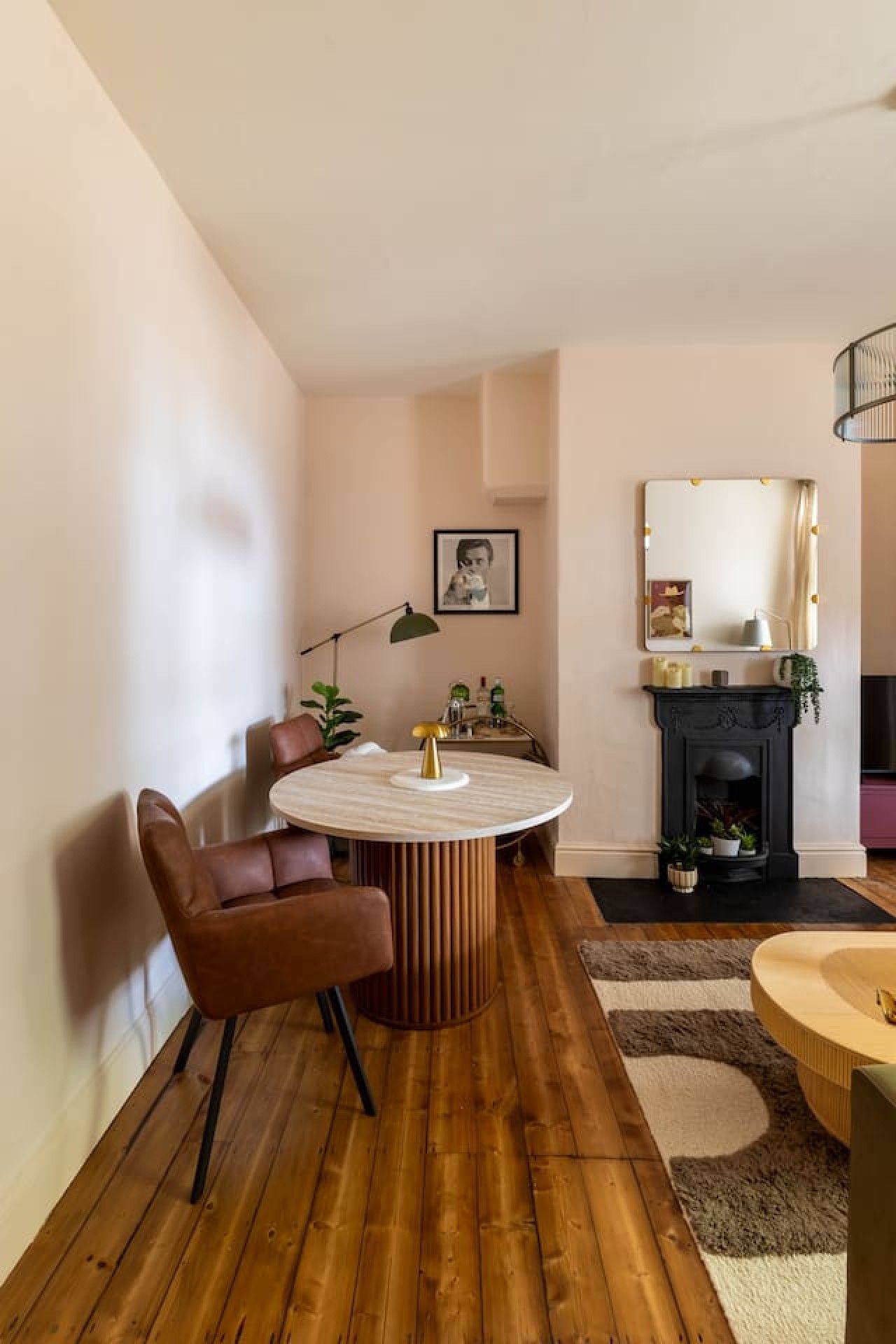 A modern living room with a round coffee table, a fireplace, and a mirror with lights.