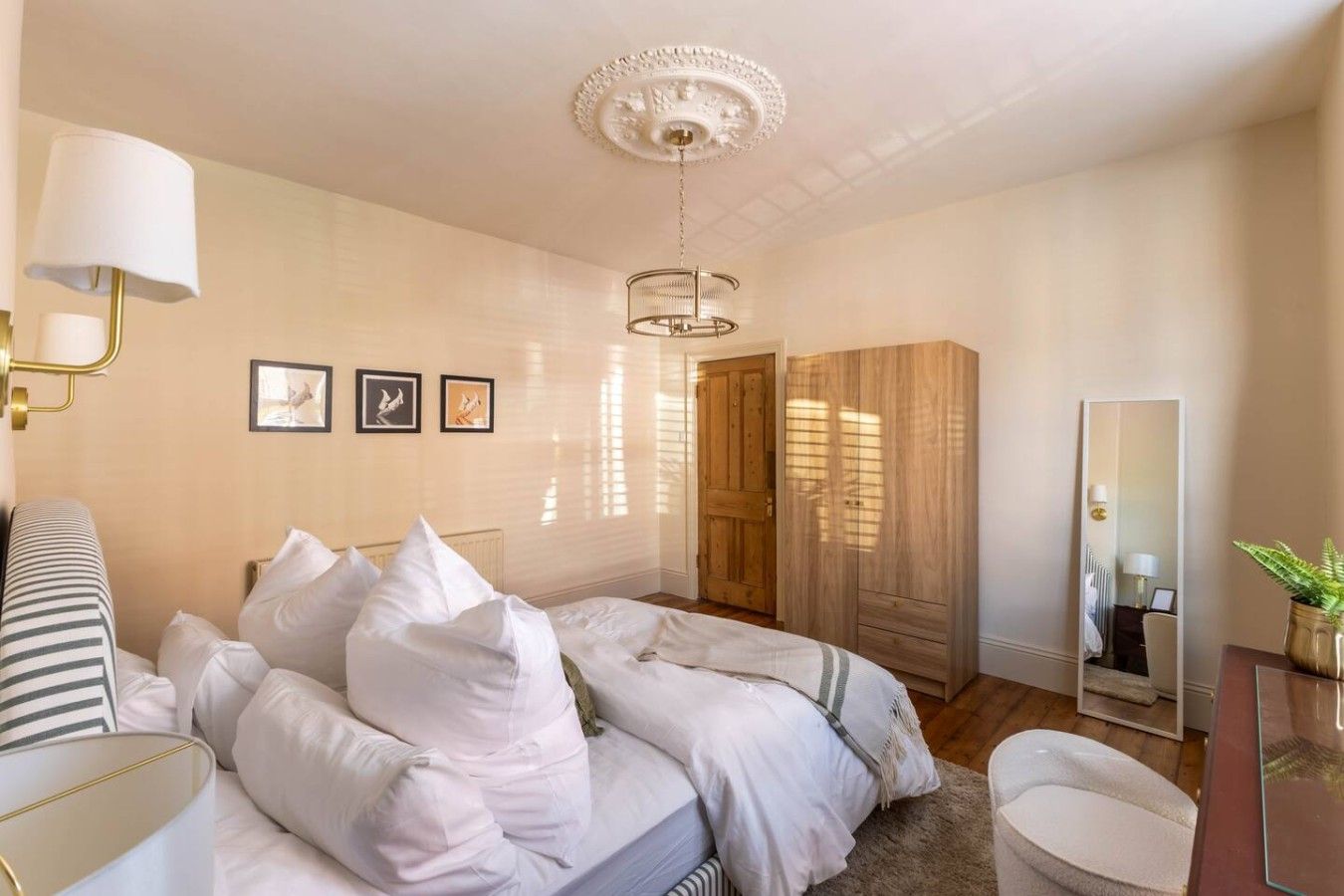 A bedroom with a bed, bedside lamps, a mirror, and a wardrobe.
