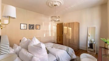 A bedroom with a bed, bedside lamps, a mirror, and a wardrobe.