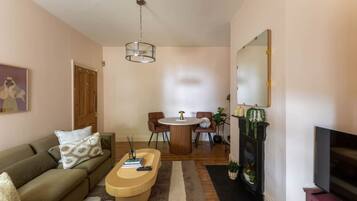 A living room with a sofa, coffee table, fireplace, TV, and a dining area with chairs and a table.