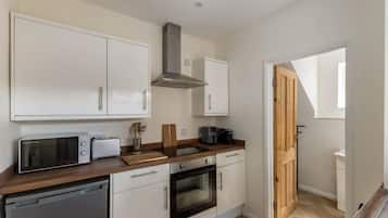 A kitchen with white cabinets, a microwave, a toaster, a coffee maker, and a wooden cutting board.