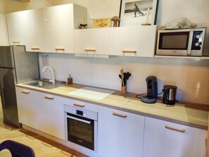 A modern kitchen with white cabinets, a stainless steel refrigerator, a built-in oven, a microwave, and a coffee maker. - 40m from ski slopes, 3rd floor, fitness, swimming pool, sauna, balcony, tv, ski locker, 51m² (Les Orres)