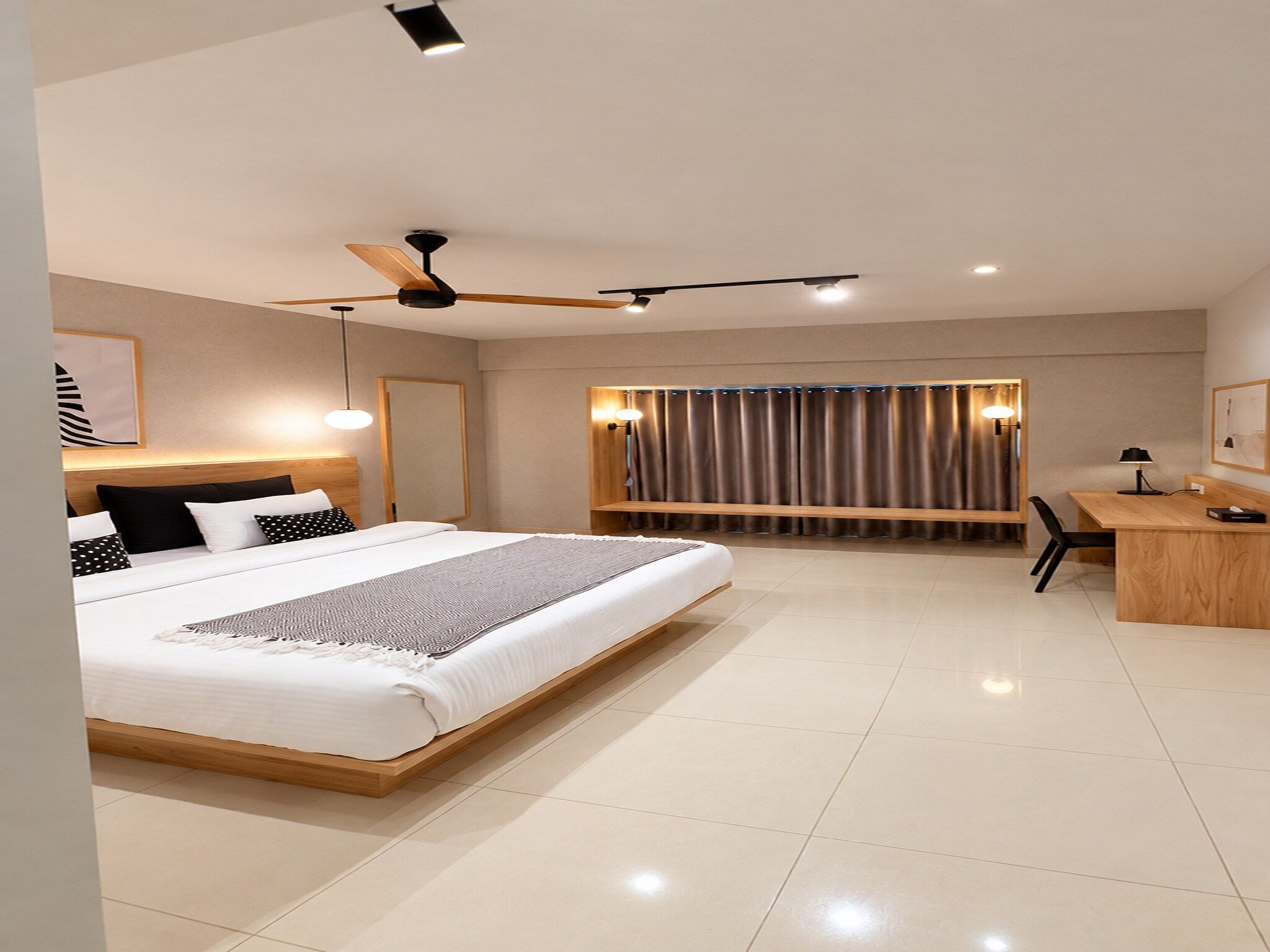 Una habitación de hotel moderna con una cama grande, un escritorio y un ventilador de techo.
