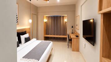A modern hotel room with a bed, desk, and TV.