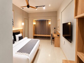 Une chambre d’hôtel moderne équipée d’un lit, d’un bureau et d’une télévision.