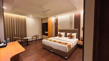 Une chambre d’hôtel équipée d’un lit, d’un bureau, d’une chaise, d’une armoire et d’un ventilateur de plafond.