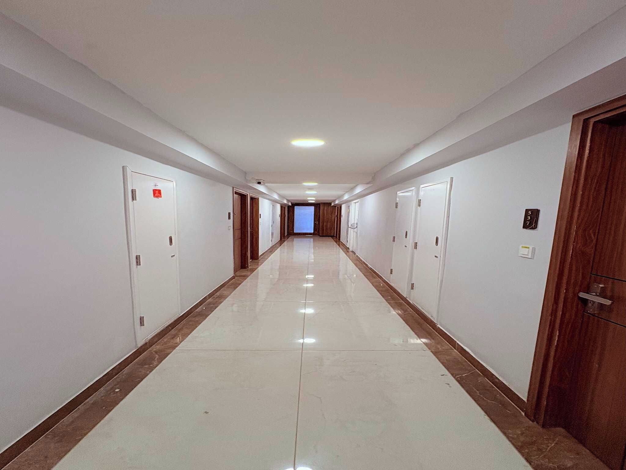 Ένας μακρύς, στενός διάδρομος με πόρτες και στις δύο πλευρές, που οδηγεί σε ένα φωτεινό δωμάτιο στο τέλος.