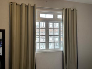 Quarto com janela, cortinas e parede.