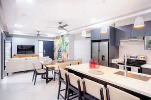 A modern kitchen with a central island, built-in appliances, and a dining area with a TV and seating. - New Listing • Dos Mangos • 3BR Walk to Beach • Playas del Coco (Playas del Coco)