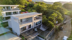 A modern two-story building with a flat roof, large windows, and a balcony on the upper floor. - New Listing • Dos Mangos • 3BR Walk to Beach • Playas del Coco (Playas del Coco)