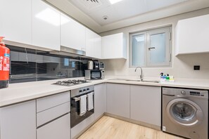 Une cuisine moderne avec des meubles blancs, une cuisinière à gaz, un four à micro-ondes et un lave-vaisselle encastré.