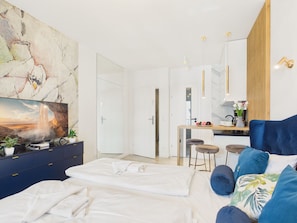 Ein modernes Hotelzimmer mit einem Bett, einem Schreibtisch, einem Sessel, einem Fernseher und einem großen abstrakten Gemälde an der Wand.
