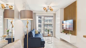 Un salon moderne avec un canapé bleu, une lampe sur pied, un téléviseur fixé sur un mur en panneaux de bois et une grande fenêtre.