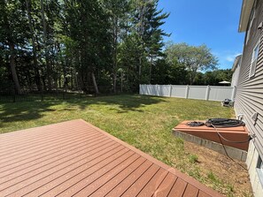 A backyard with a wooden deck, a white fence, and a hose on the deck. - Ebb Tide Way Wells Retreat (Wells)