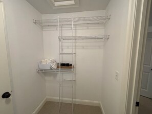Ein begehbarer Kleiderschrank mit Metallregalen, einer Tür und einem Teppichboden.