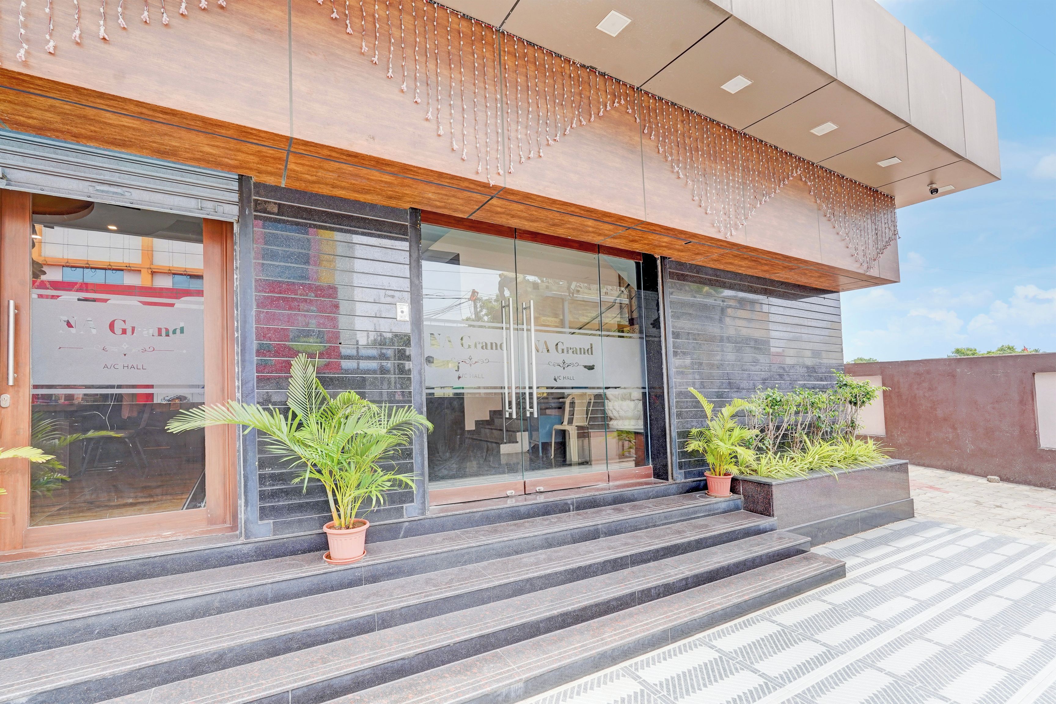 Un edificio moderno con fachada de vidrio, detalles de madera y mobiliario exterior.