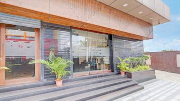 Un edificio moderno con fachada de vidrio, detalles de madera y mobiliario exterior.