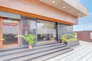 Un edificio moderno con fachada de vidrio, detalles de madera y mobiliario exterior.