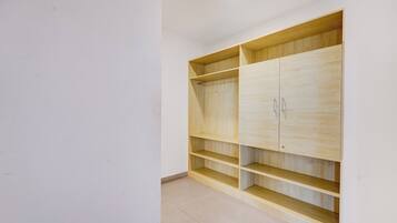 Una habitación con un armario de madera, varios estantes y suelo de baldosas.