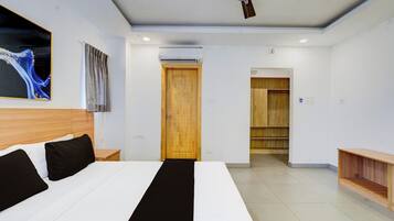 Habitación de hotel moderna con una cama grande, un ventilador de techo, una puerta de madera y vistas al pasillo.