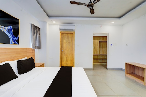 Habitación de hotel moderna con una cama grande, un ventilador de techo, una puerta de madera y vistas al pasillo.