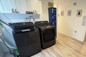 A laundry area with two black LG washing machines, a staff-only sign above a door, and a Wi-Fi sign on the wall. - Charming 4 bedroom 2 bath house in Hallandale (Hallandale)