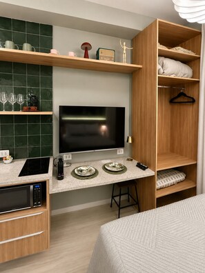 A modern kitchenette with a built-in microwave, stove, and a flat-screen TV. - SETIN 2304 (São Paulo)